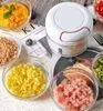 A white manual food chopper is surrounded by bowls of chopped ingredients like corn, ham, and herbs. Produktbild-Vorschau