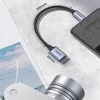A Ugreen USB-C to USB-A adapter cable is shown connected to a smartphone, with a camera lens in the foreground. Podgląd zdjęcia produktu