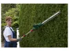 A woman is using a telescopic hedge trimmer to trim a tall hedge. Produktbild-Vorschau