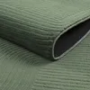 A close-up view of a green rug with a geometric pattern, showing the texture and the edge of the rug. Podgląd zdjęcia produktu