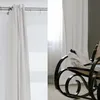 A white curtain hangs on a rod on the left, and a rocking chair with a white cloth draped over it is visible on the right. Produktbild-Vorschau