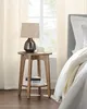 A bedside table with a lamp and candle next to a bed. Produktbild-Vorschau