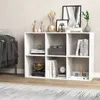 A white cube bookshelf filled with decorative items and books, placed in a room next to a sofa. Náhľad obrázku produktu