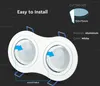 A marketing image showing a white double LED spotlight with blue mounting clips. Text overlays describe installation and product specifications. Voir les images du produit