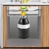A kitchen sink with a garbage disposal unit installed underneath, showing food waste being processed. Produktbild-Vorschau