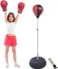 A young girl in boxing gloves and shorts stands with her arms raised next to a punching bag set. A pump is also visible. Produktbild-Vorschau