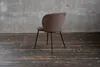 A brown corduroy chair with black metal legs is placed on a dark wooden floor in front of a concrete wall. Produktbild-Vorschau