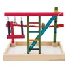 A colorful bird play stand with various perches, swings, and ladders, set on a white background within a wooden tray. Náhled obrázku produktu