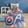A child's bed with Marvel Avengers themed bedding, a bedside table with books and a lamp, and a blue floor cushion. Produktbild-Vorschau