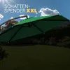 A large green cantilever umbrella is set up in a garden on a sunny day. Produktbild-Vorschau