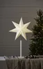 A star-shaped lamp sits on a table next to a decorated Christmas tree. Podgląd zdjęcia produktu