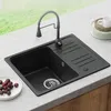 A black granite kitchen sink with a faucet and a small dish of cherries on a countertop. Produktbild-Vorschau
