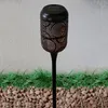 A solar-powered garden light with a decorative metal casing is shown outdoors, placed in gravel and artificial grass. Produktbild-Vorschau