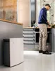 A man is in a kitchen preparing food, with an air purifier in the foreground. Produktbild-Vorschau