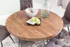 A round wooden dining table with chairs, a bowl, and apples on it, set in a dining room. Produktbild-Vorschau