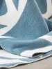 A close-up view of a folded blue and white patterned blanket. Anteprima dell’immagine prodotto