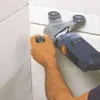 A person is using a power tool to cut into a textured wall. Anteprima dell’immagine prodotto