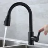 A black kitchen faucet with water running into a sink, with a hand operating the handle. Produktbild-Vorschau