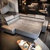 A modern living room with a large sectional sofa and a spiral staircase in the background. Produktbild-Vorschau