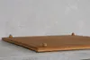 A close-up, angled view of a bamboo cutting board with four small wooden feet, resting on a countertop against a textured gray wall. Produktbild-Vorschau