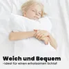 A young girl is sleeping on a white bed, hugging a white pillow. Produktbild-Vorschau