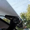 A dashcam is mounted on a car windshield, with trees and sky visible through the glass. Produktbild-Vorschau