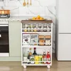A slim storage cart filled with various kitchen items like spices, bottles, and cans, placed next to a refrigerator in a kitchen setting. Anteprima dell’immagine prodotto