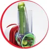 A close-up of a zucchini being inserted into a food processor attachment. Náhled obrázku produktu