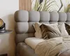 A close-up view of a bed with a tufted headboard and pillows. Náhled obrázku produktu