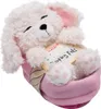 A white plush dog toy with pink accents, sleeping in a pink basket, with a product tag attached. Produktbild-Vorschau