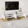 A white TV stand with gold legs and handles, featuring open doors and shelves, is shown in a living room setting with a large TV mounted above it. Produktbild-Vorschau
