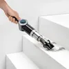 A hand is holding a black and clear handheld vacuum cleaner and cleaning the steps of a white staircase. Produktbild-Vorschau