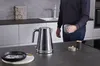 A person holding a mug in a modern kitchen with a kettle on the counter. Anteprima dell’immagine prodotto