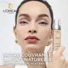 A woman holds a bottle of L'Oréal Paris True Match foundation in front of a white background, with marketing text overlaid. Voir les images du produit