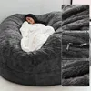 A woman is relaxing on a large, plush beanbag chair, covered with a white blanket. Produktbild-Vorschau