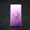 A purple Samsung Galaxy S9 Plus smartphone with a large '9' graphic on its screen, set against a dark, textured background. Produktbild-Vorschau