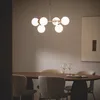 A dining table set with wine glasses and cutlery, illuminated by a modern chandelier. Produktbild-Vorschau