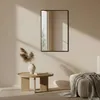 A minimalist living room scene with a mirror, coffee table, and sofa. Anteprima dell’immagine prodotto