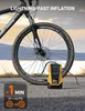 A yellow and black portable air compressor is connected to a bicycle tire, with the bicycle wheel in the foreground. The background shows a body of water and a distant shore. Podgląd zdjęcia produktu