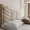 A close-up view of a modern bed with a plush, upholstered headboard and bedding. Produktbild-Vorschau