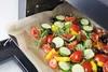 A baking sheet filled with chopped vegetables and herbs is being placed into an oven. Náhled obrázku produktu