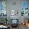 A white vanity table with LED lights and a stool is set up in a room with two large windows showing a winter landscape. Voir les images du produit