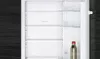 An open refrigerator showing multiple shelves and a bottle. Produktbild-Vorschau