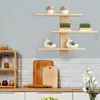 A wooden shelf unit with decorative items is mounted on a light blue wall above a kitchen counter. Produktbild-Vorschau