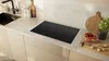 A modern kitchen countertop with an induction hob, sink, and decorative items. Voir les images du produit