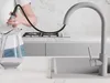 A person is using a pull-out faucet to fill a glass pitcher in a modern kitchen. Produktbild-Vorschau