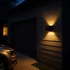 A car parked in front of a garage at night, with a wall light illuminating the side of the house. Náhľad obrázku produktu