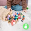 A child's hands are reaching into a beige cloth bag filled with colorful wooden blocks and toy vehicles, which are scattered on a white, fluffy rug. Náhled obrázku produktu