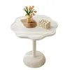 A white, flower-shaped side table with decorative items on top. Produktbild-Vorschau