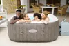 Four people are enjoying a hot tub on a patio. Produktbild-Vorschau